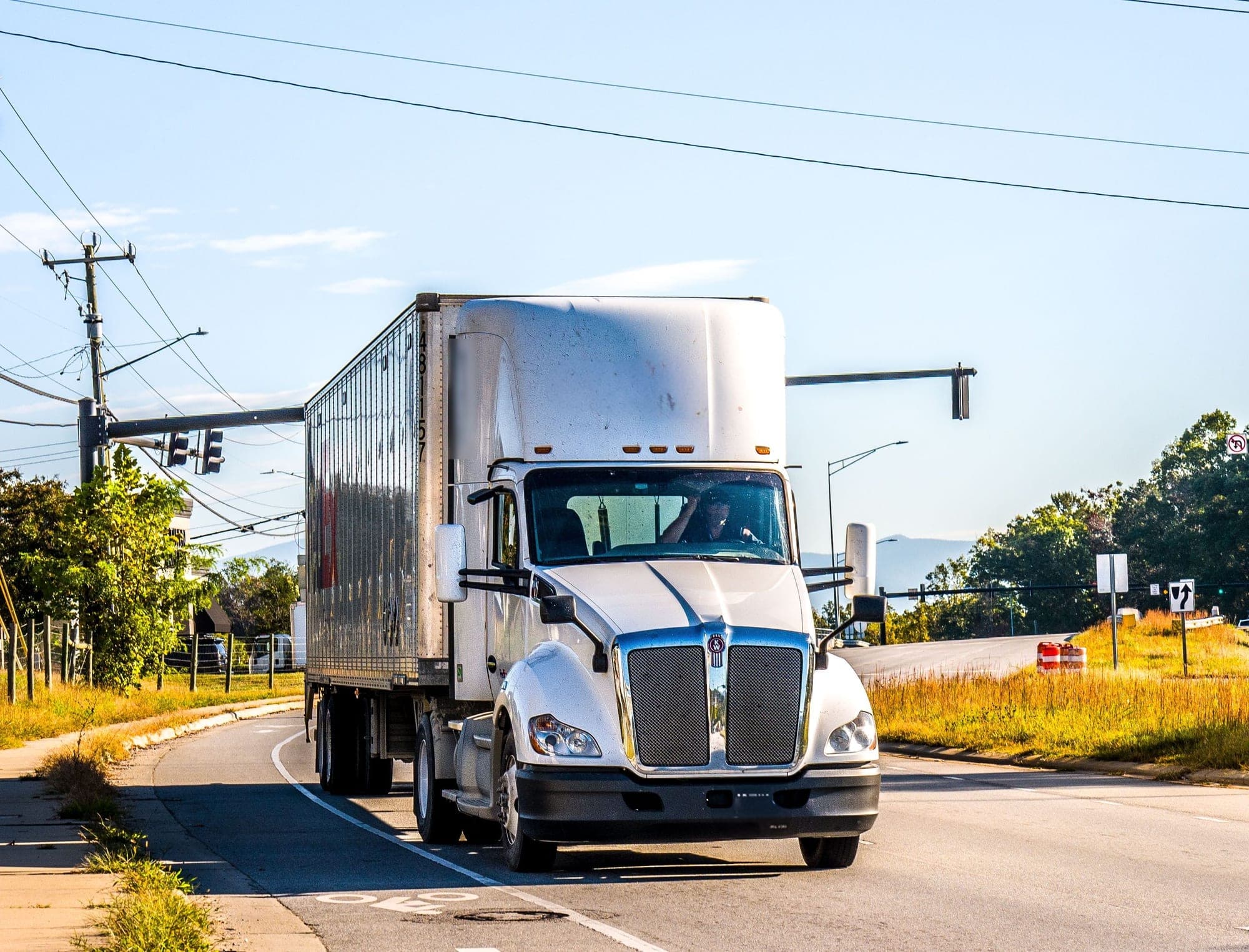 White semi-truck pulling an enclosed dry van trailer on a sunny road (illustrative photo, not our vehicle)
