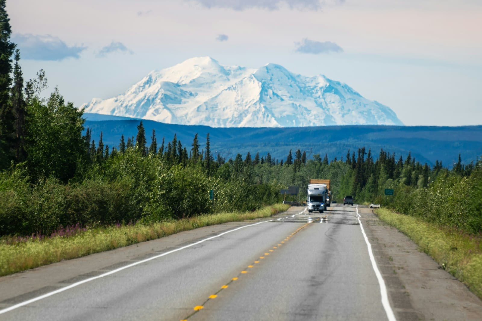 Highway through spruce forest toward a snow-covered Denali in Alaska